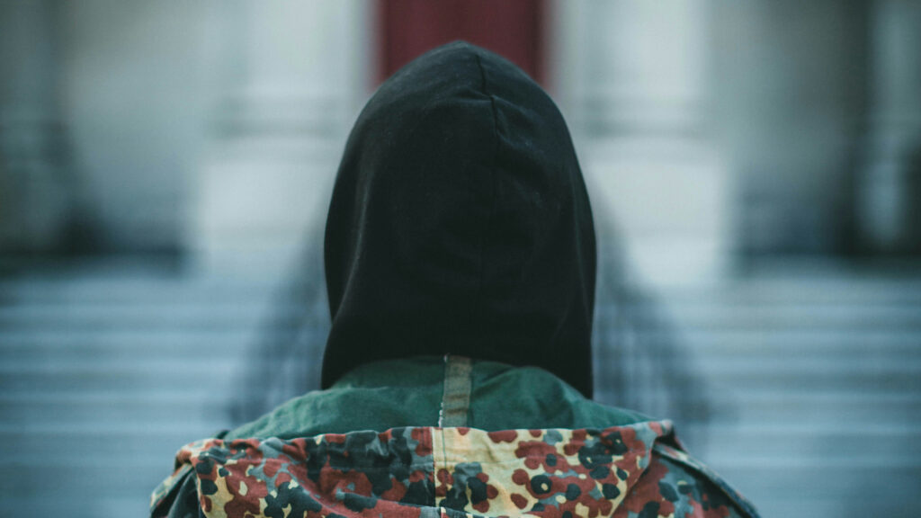 Person med hette bakfra foran en trapp.