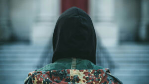 Person med hette bakfra foran en trapp.