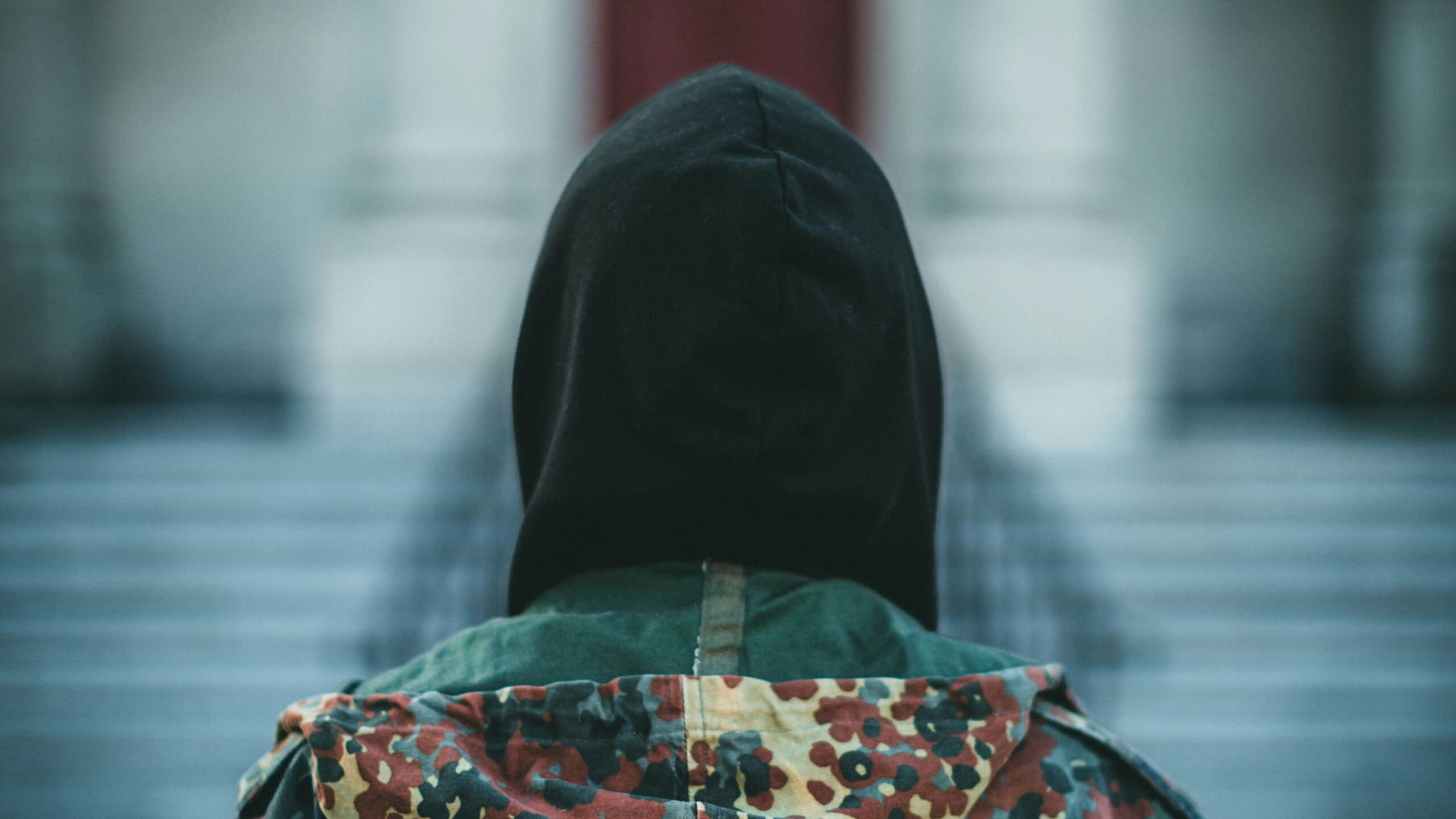 Person med hette bakfra foran en trapp.